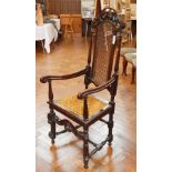 A pair of 17th century style oak high back armchairs, with carved crest rails, cane panel backs,