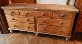 A Victorian pine sideboard with two short and five long drawers, on bun feet,