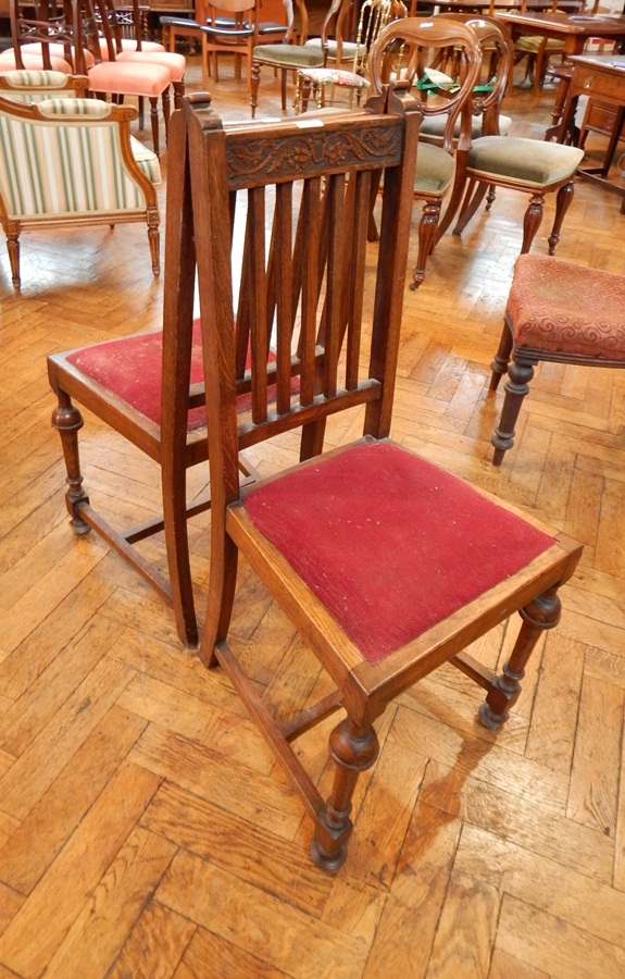 A pair of oak high back dining chairs with carved crest rail and open splats,