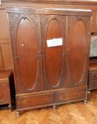 An early 20th century oak bedroom suite viz:- wardrobe with floral engraving to door panels and two