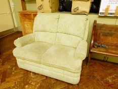A two seater sofa with green weave and floral decoration,