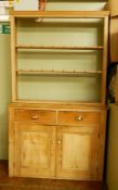 A pine dresser fitted with two short drawers over a pair of panelled cupboard doors,