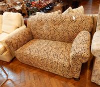 A small two seater sofa with floral upholstery on bun feet,