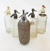 Five vintage soda syphons, one labeled "C & C Club Soda Water" and one with plaited metal casing.