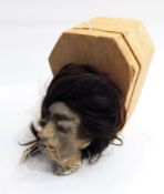 An imitation shrunken head in a cork coffin-shaped box and a flag