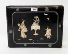 A lacquered papier mache postcard album with applied bone and mother-of-pearl decoration with inset