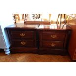 A pair of bedside chests with two short drawers, swan neck handles, on block feet,