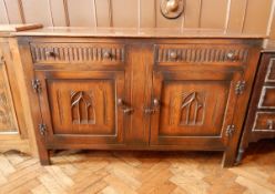 An oak sideboard with two short drawers and two cupboards, lancet carving,