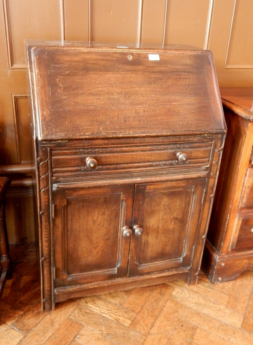 An oak bureau with one long frieze drawer and two cupboards, fitted interior,
