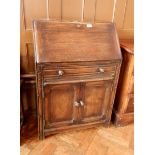 An oak bureau with one long frieze drawer and two cupboards, fitted interior,