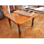 A Victorian walnut wind-out dining table with spare leaf,