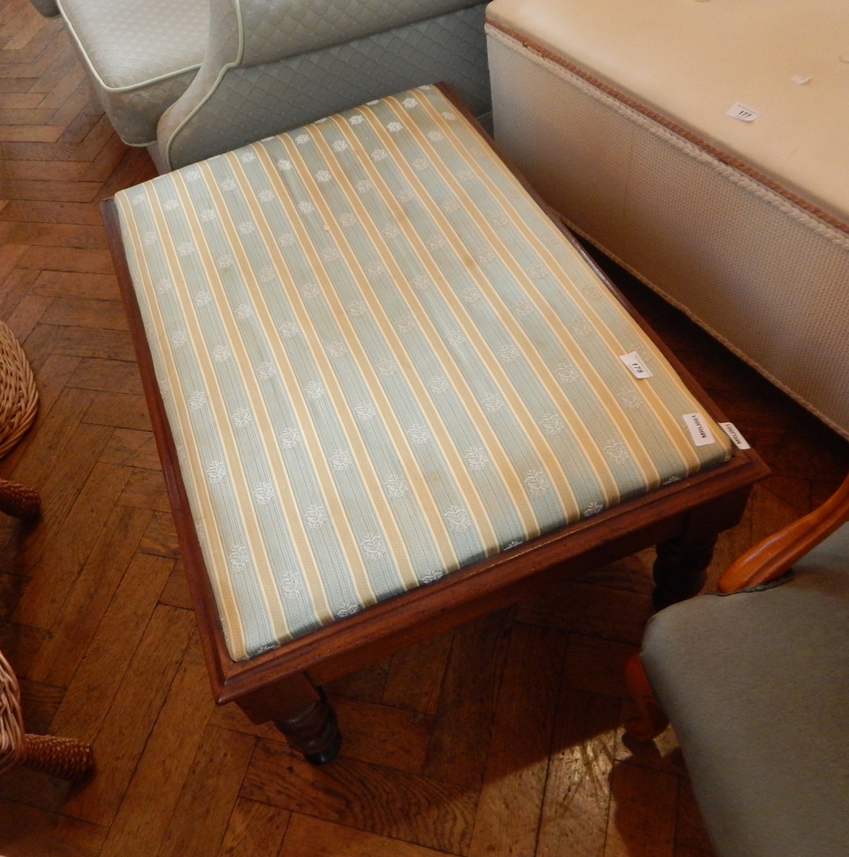 A mahogany footstool with green and gold fabric top, floral decoration,