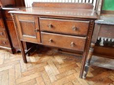 An oak side table with raised back and beaded border, cupboard and two graduating long drawers,