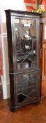 A stained oak floor standing corner cupboard with glazed front and four shelves,