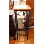 A glass topped plant stand with wrought iron supports and floral decoration