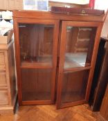 An oak bookcase on stand, with glass panelled doors and two shelves,