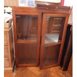 An oak bookcase on stand, with glass panelled doors and two shelves,