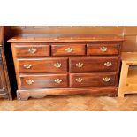 A stained wood low dresser with three short and four long drawers with swan neck handles,