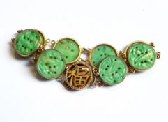 A Chinese gold and jade bracelet comprising eight circular carved jade discs decorated with birds,