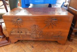 A hardwood coffer with oriental carved scene to lid and base, on shaped bracket feet,