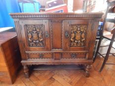 An oak Victorian side cabinet with coat of arms, on cup and ball and block feet,