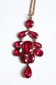 A gold pendant set with synthetic rubies in collet settings, on a gold belcher link chain,