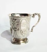 A Victorian silver mug with flared rim, floral repousse decoration, raised on a circular foot,