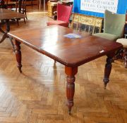 An walnut dining table with one leaf inset, on reeded supports and castors,