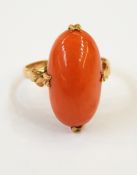 A gold and coral ring, the oval coral in a four claw setting,