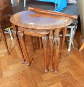 A walnut nest of three tables with scroll carving to edge,