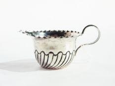 An Edwardian silver sugar bowl with cut card borders, raised on pad feet,