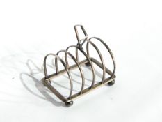 A silver four-division toast rack, Birmingham 1924 and a tea strainer,