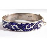 A sterling silver and enamel bangle with foliate scroll blue and white enamelling