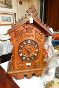 Carved oak cuckoo-style wall hanging clock with carved pierced pediment, foliate scroll decoration,