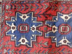 Persian red ground rug having central blue elephant guls surrounded by geometric design with