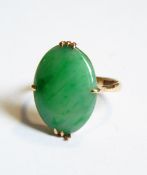A gold and jade ring, the oval jade in a four-claw setting,