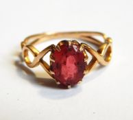 An early 19th century gold ring with pierced shoulders and a central pink paste oval stone
