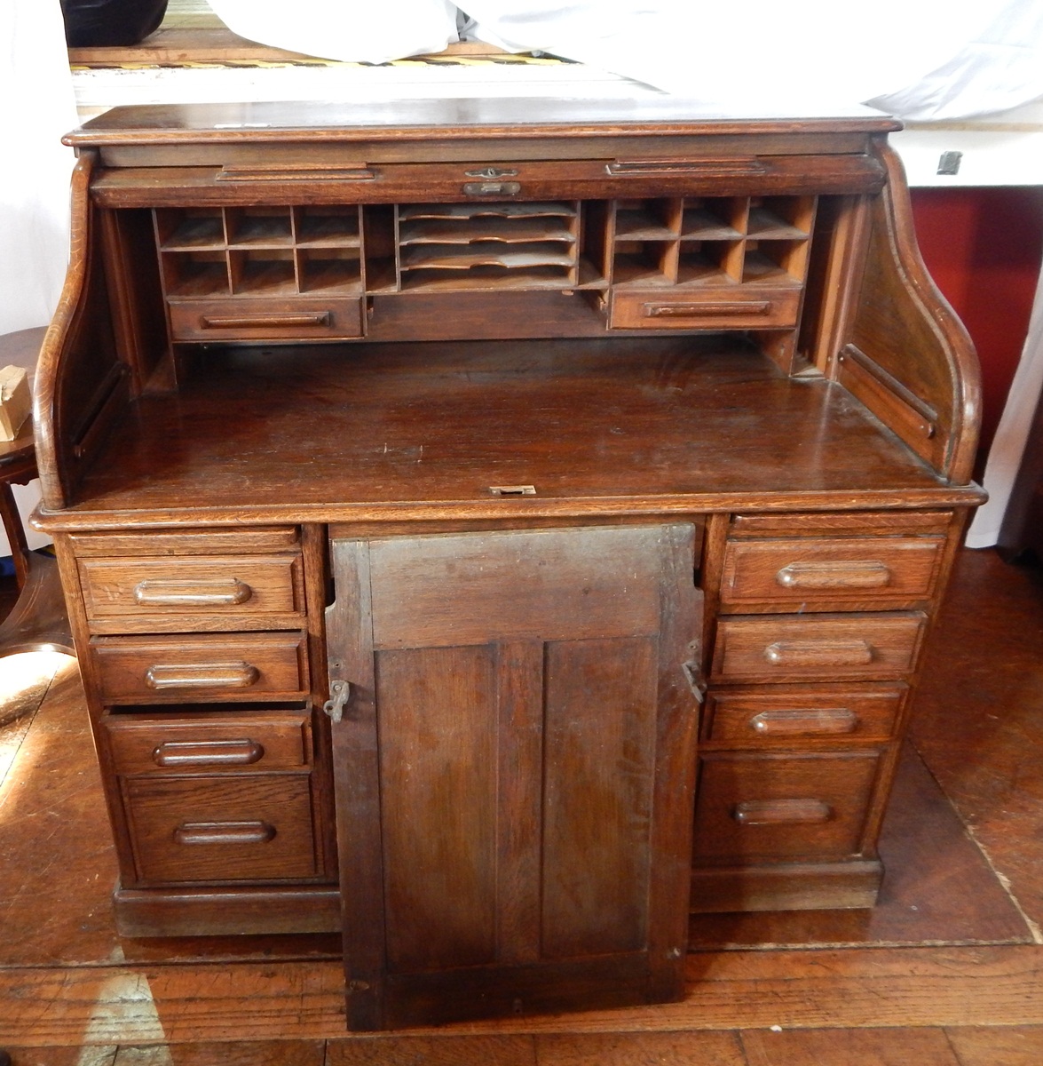 An oak roll top writing desk with sections for letters and other items,