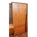 A modern pine single wardrobe, the pair of panelled doors enclosing hanging space,