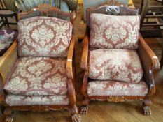 A pair of walnut framed Bergere armchairs on paw feet and with moulded and applied ornamentation