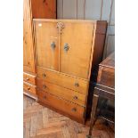 A mid 20th century oak veneer cupboard with pair panelled doors enclosing shelf,