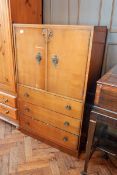 A mid 20th century oak veneer cupboard with pair panelled doors enclosing shelf,