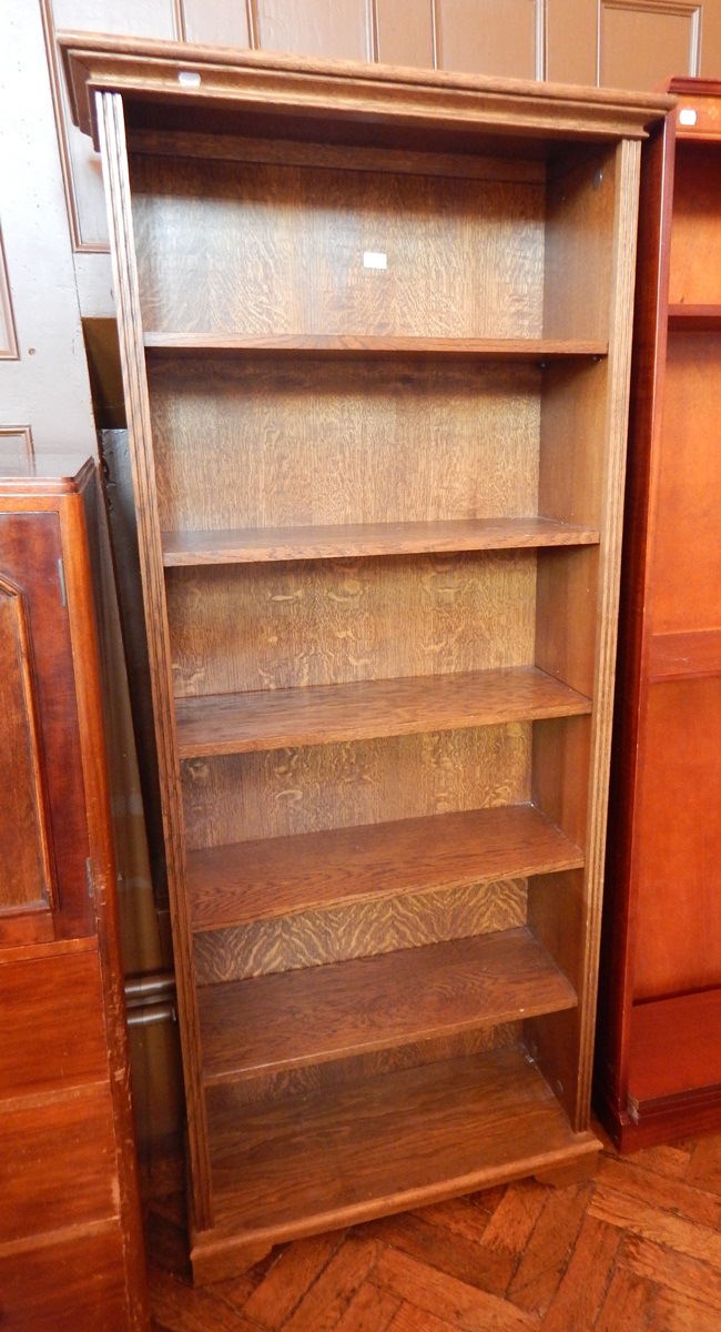 An oak open bookcase of five shelves, raised on bracket feet,