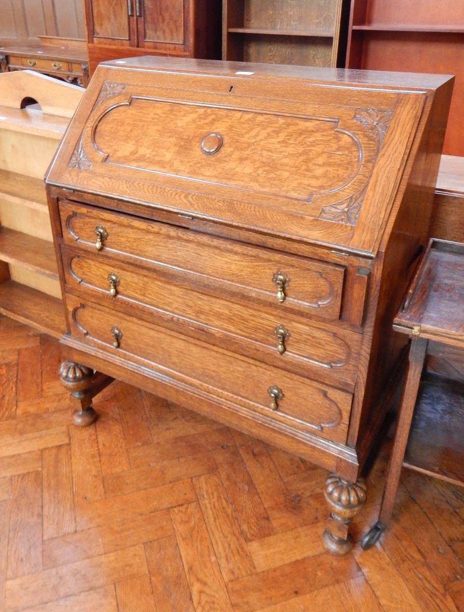 Twentieth century oak bureau with fitted interior, three long drawers on turned bulbous legs,