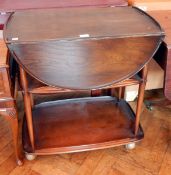 An Ercol style drop oval flap tea trolley, with two undershelves raised on castors,