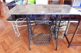 An iron Singer sewing machine stand, with treadle pedal, with a rectangular grey marble top,