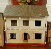 A doll's house with white front, balcony and entrance hall, opening to show separate rooms,