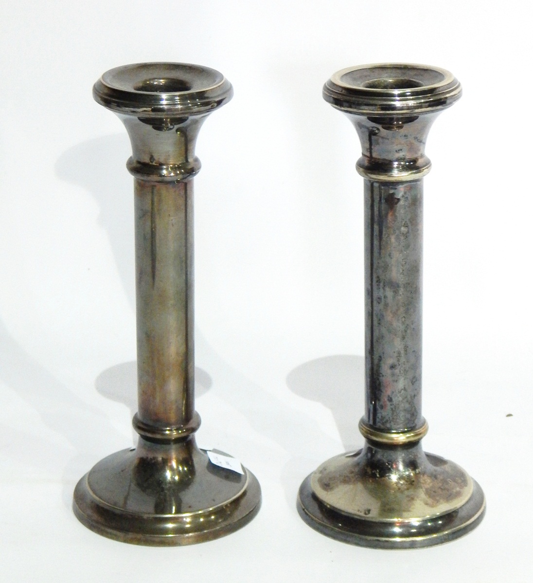 A pair of silver plated candlesticks of plain cylindrical form