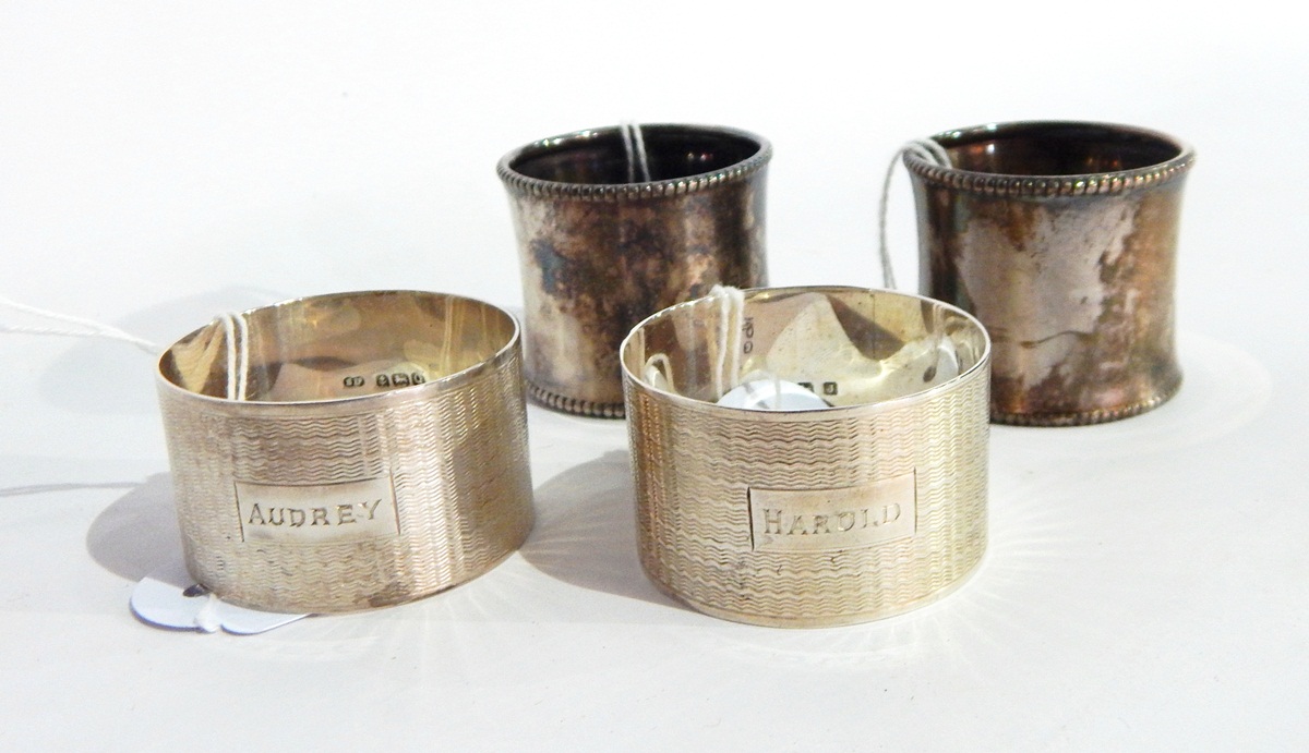 Two cased silver napkin rings of engine turned decoration and a pair of silver napkin rings with