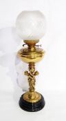 A brass oil lamp, the stem modelled as two embracing children and with globular glass shade,